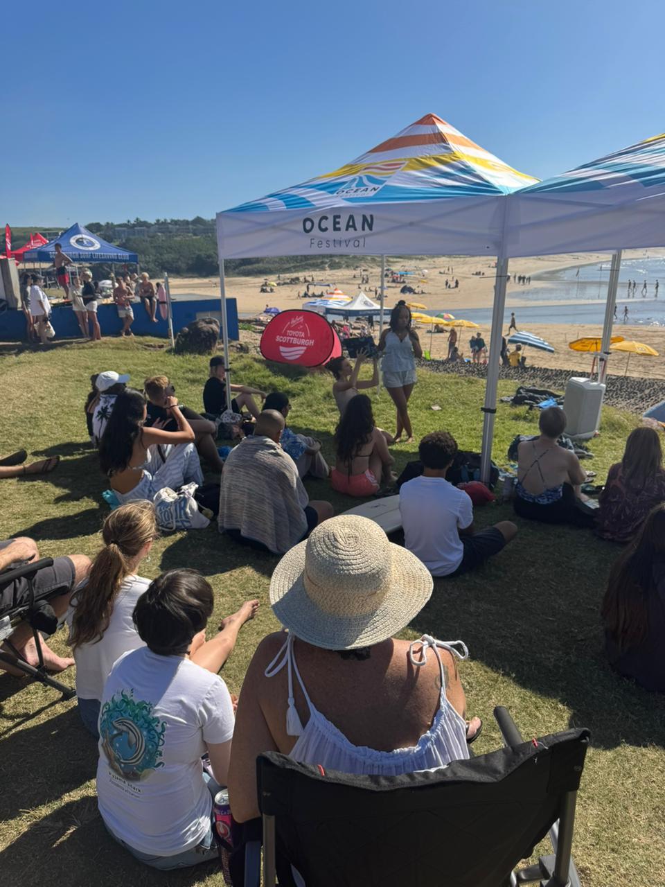 An intern presenting to a seated audience under the Ocean Festival gazebo