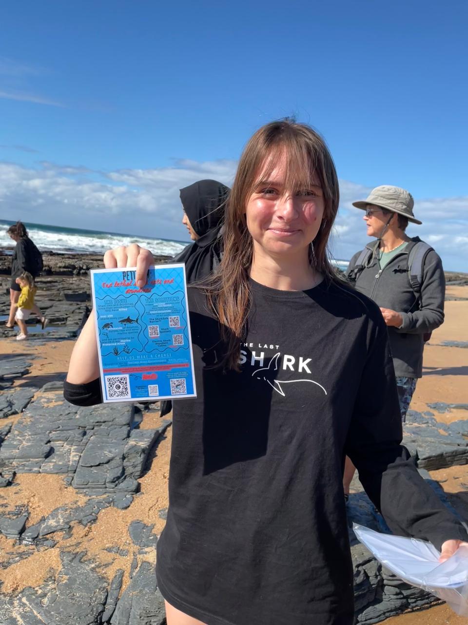 An intern holding a petition to end lethal shark nets and drumlines on the South Coast