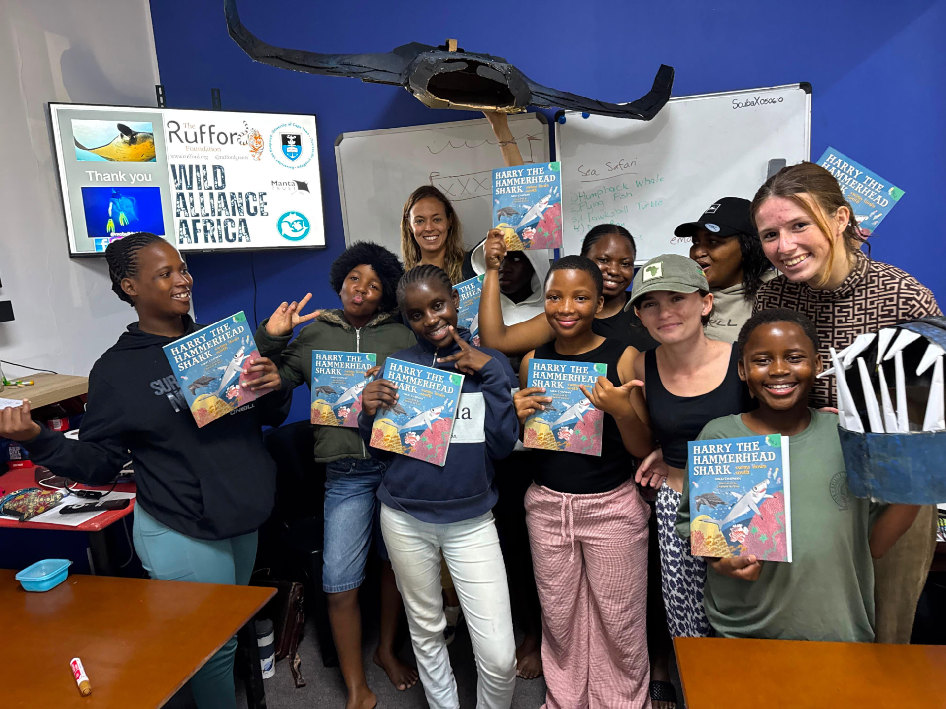 Interns and school learners holding marine conservation storybooks after a lesson